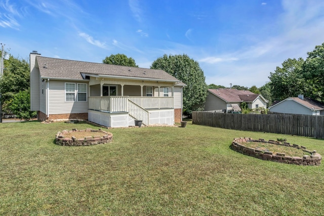 rear view of property featuring covered porch, a chimney, fence, and a yard