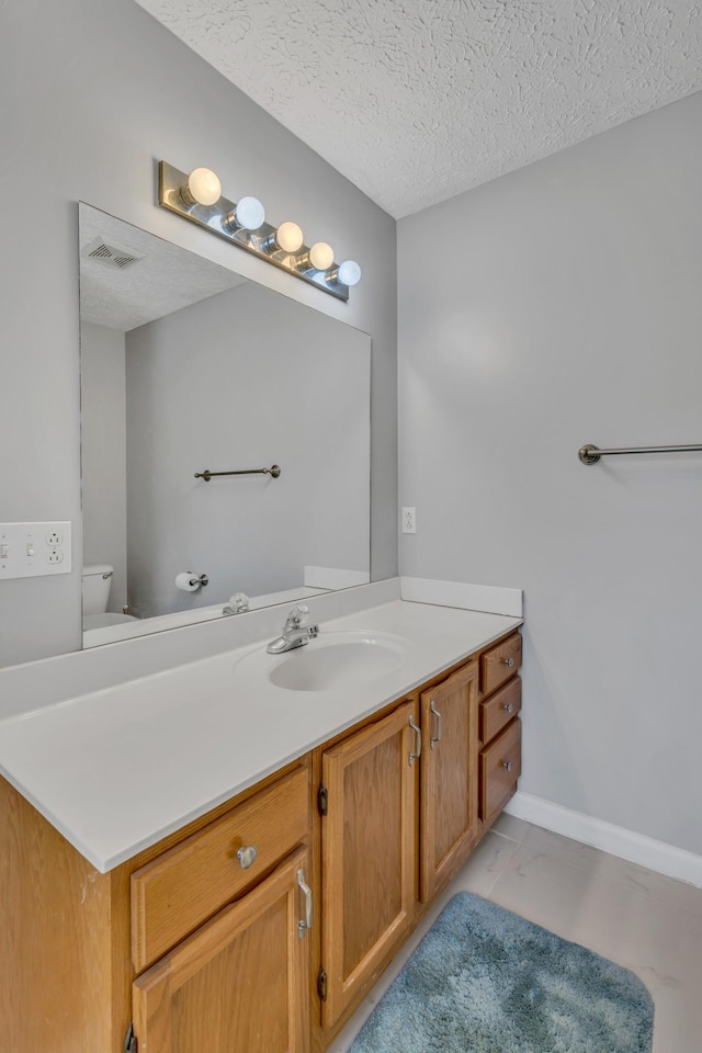 bathroom featuring visible vents, toilet, marble finish floor, a textured ceiling, and vanity