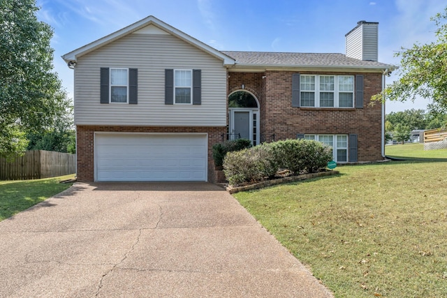 split foyer home featuring brick siding, a chimney, concrete driveway, a front yard, and fence