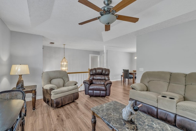 living area with light wood-style flooring, baseboards, and a textured ceiling