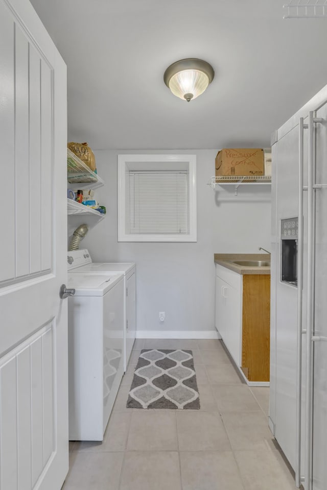 clothes washing area featuring cabinet space, light tile patterned flooring, a sink, separate washer and dryer, and baseboards