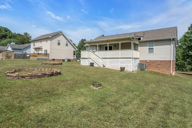 rear view of house featuring an outdoor structure, central AC, a lawn, and brick siding