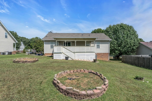 rear view of house featuring covered porch, a lawn, central AC unit, and fence