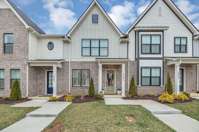 multi unit property featuring brick siding, board and batten siding, and a front lawn