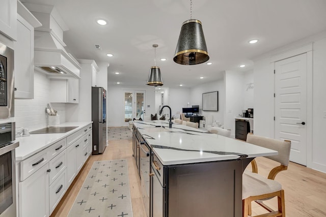 kitchen featuring a large island, open floor plan, stainless steel appliances, light countertops, and white cabinetry