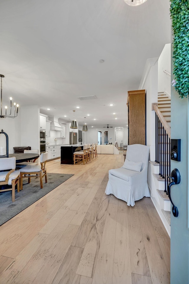 living room with light wood-type flooring, stairs, a notable chandelier, and recessed lighting