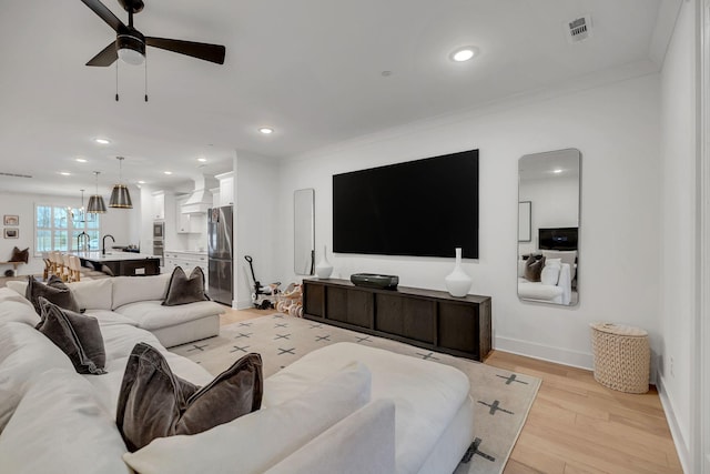 living room with light wood finished floors, recessed lighting, visible vents, ornamental molding, and baseboards