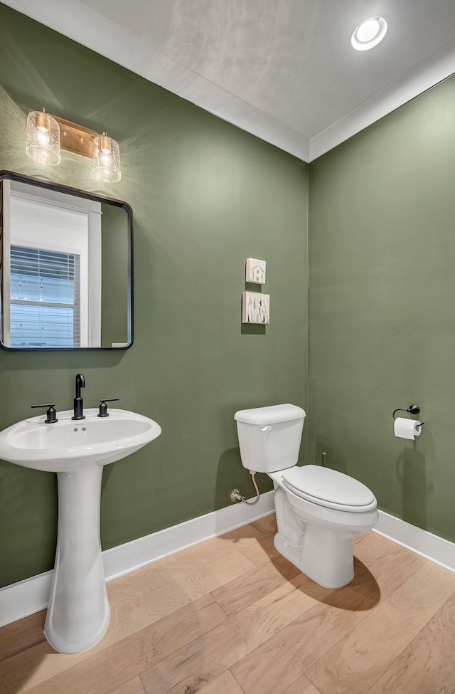 half bathroom with baseboards, a sink, and toilet