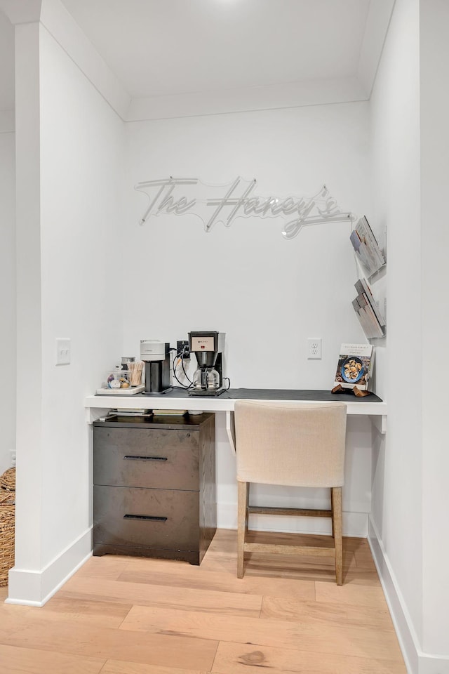 bar featuring ornamental molding, light wood-type flooring, built in desk, and baseboards