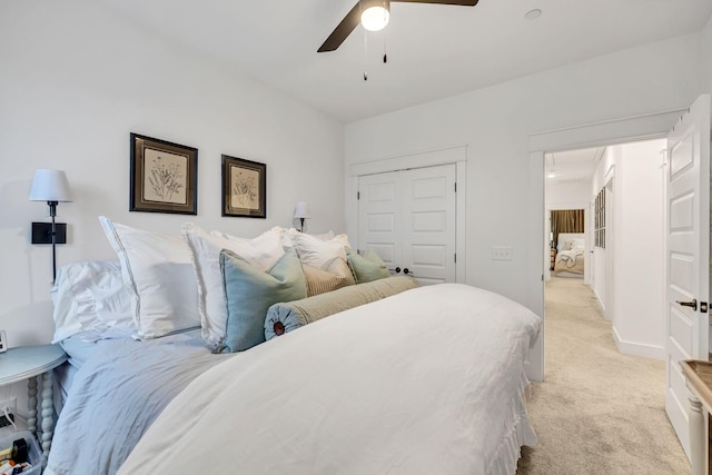 bedroom featuring a closet, a ceiling fan, attic access, light carpet, and baseboards