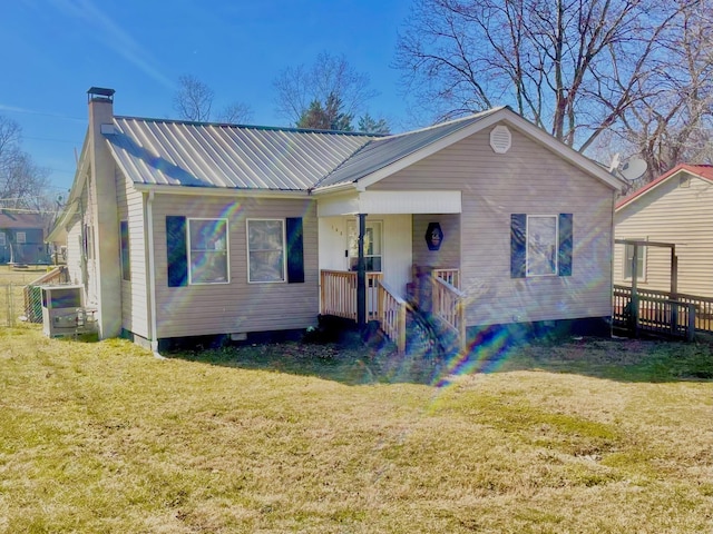 view of front of house featuring metal roof, a chimney, a porch, and a front yard