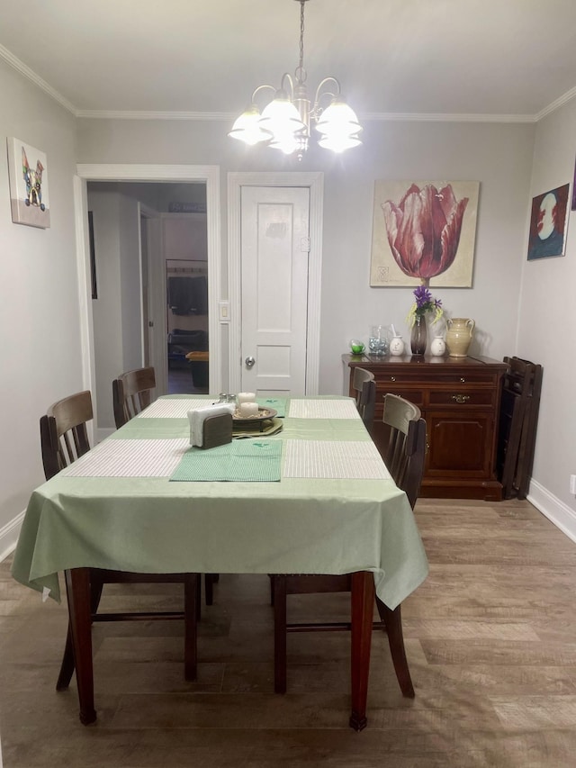 dining space with light wood-type flooring, baseboards, ornamental molding, and a chandelier