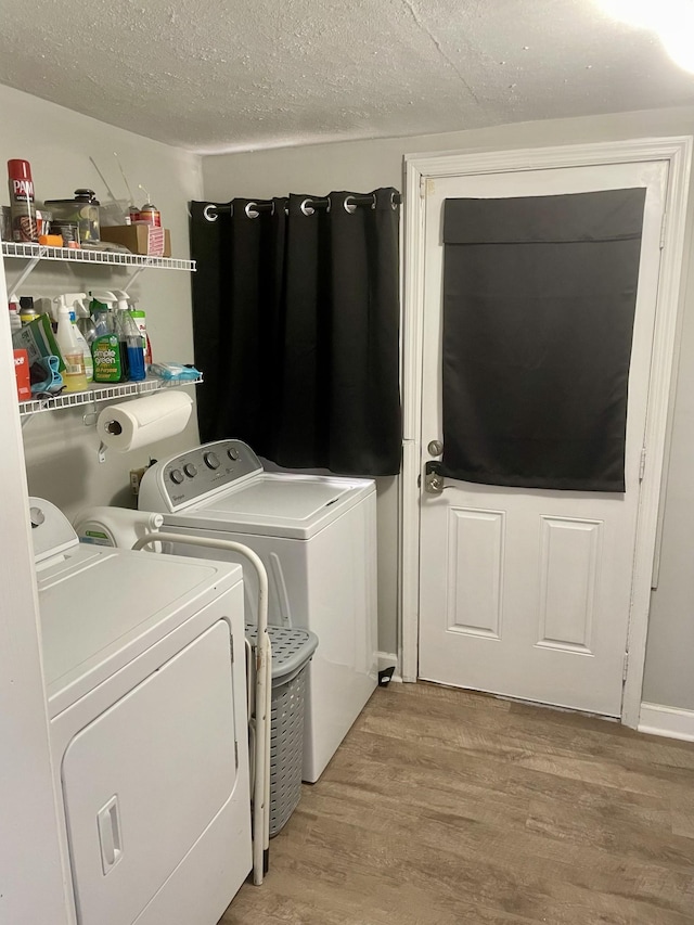 clothes washing area with light wood-style floors, washer and dryer, laundry area, and a textured ceiling