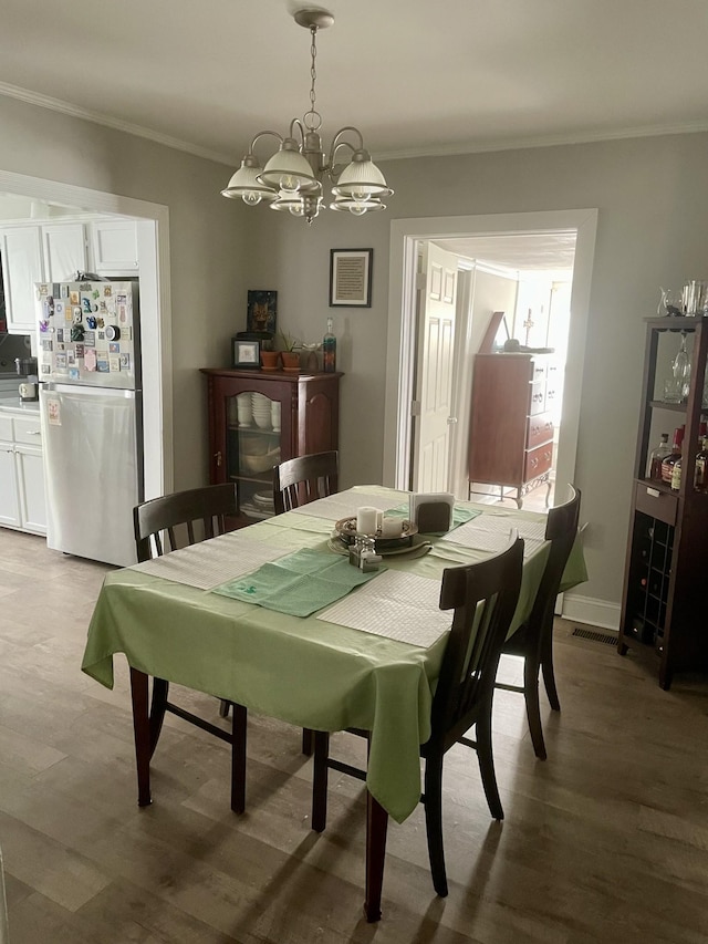 dining area with light wood-type flooring, an inviting chandelier, baseboards, and crown molding