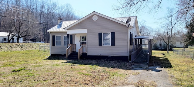 view of front of home with a front yard, metal roof, fence, and a chimney