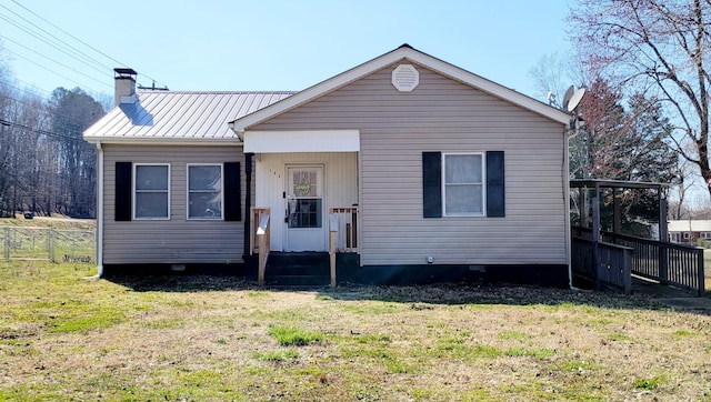 bungalow-style house featuring metal roof, a chimney, a front yard, and fence