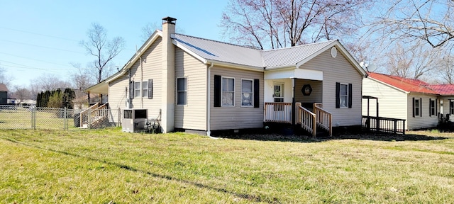 view of front of home with central AC, fence, a front yard, metal roof, and a chimney