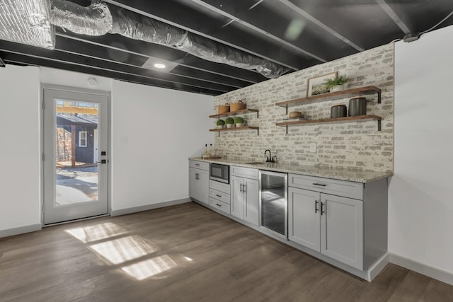 bar featuring black microwave, wine cooler, dark wood-type flooring, and wet bar