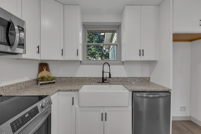 kitchen with appliances with stainless steel finishes, white cabinets, and a sink