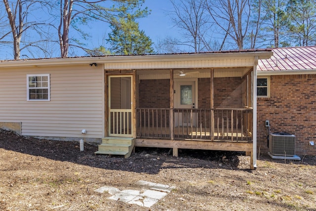 view of exterior entry featuring metal roof, brick siding, and central air condition unit