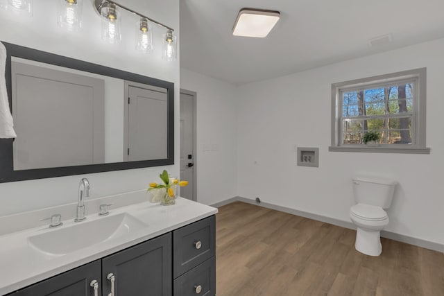 bathroom with vanity, wood finished floors, toilet, and baseboards