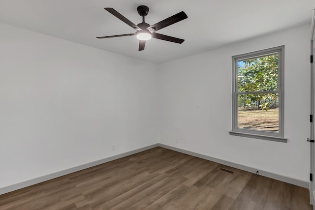 spare room featuring visible vents, ceiling fan, baseboards, and wood finished floors