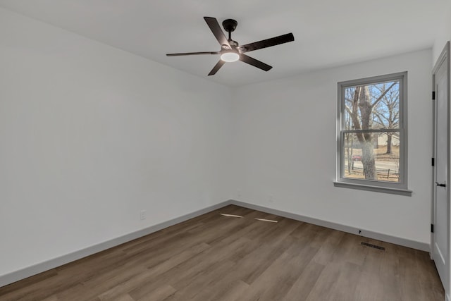 unfurnished room with a ceiling fan, visible vents, baseboards, and wood finished floors