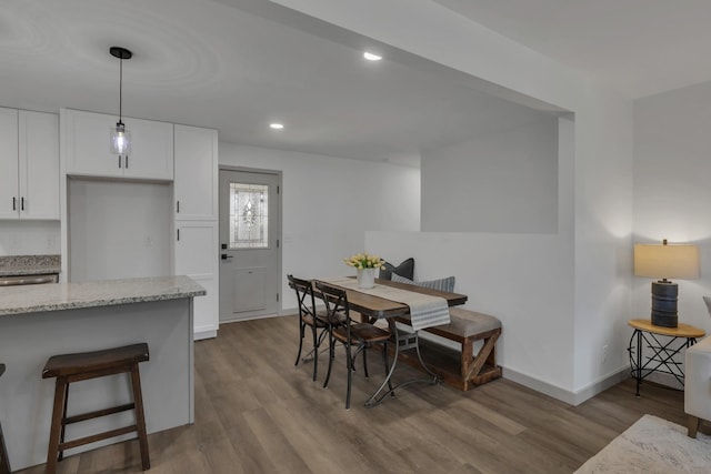 dining area featuring baseboards, wood finished floors, and recessed lighting