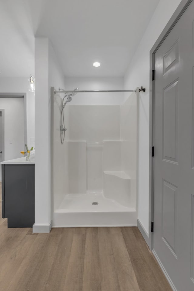 bathroom with wood finished floors, vanity, and walk in shower