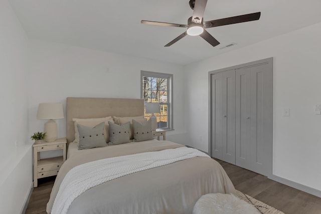 bedroom with a closet, visible vents, a ceiling fan, wood finished floors, and baseboards