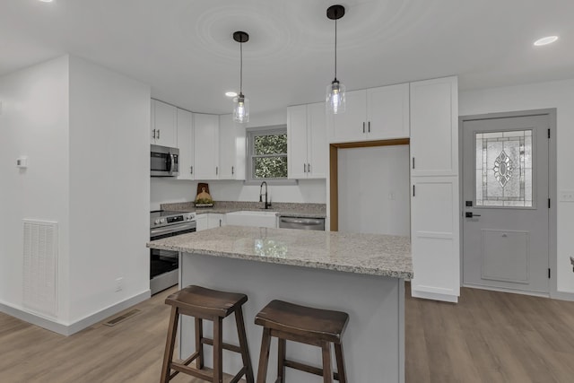 kitchen with white cabinetry, visible vents, appliances with stainless steel finishes, and a kitchen breakfast bar