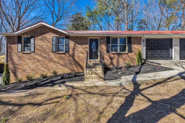 single story home featuring an attached garage, metal roof, concrete driveway, and brick siding