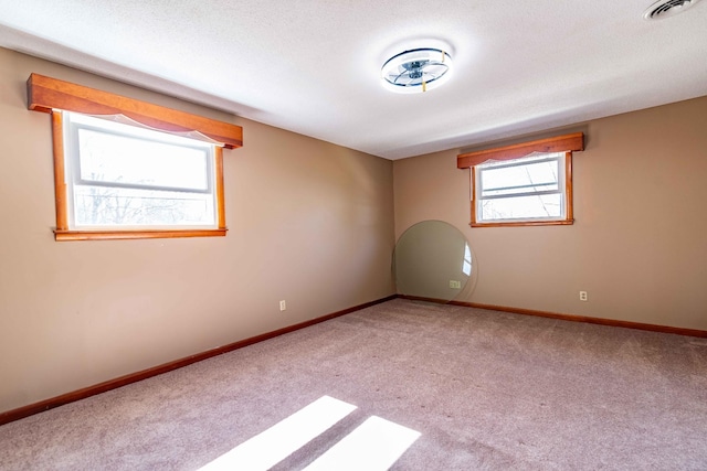 carpeted spare room with visible vents, a textured ceiling, and baseboards