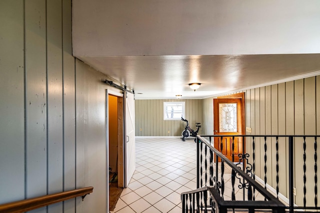 hallway featuring baseboards, a barn door, an upstairs landing, and tile patterned floors