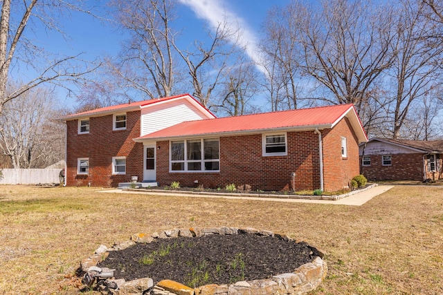 split level home with metal roof, brick siding, fence, and a front lawn