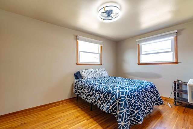 bedroom featuring multiple windows, wood finished floors, and baseboards