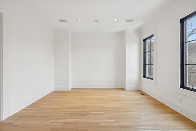 spare room featuring light wood-style flooring, ornamental molding, and baseboards