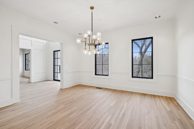 spare room featuring light wood finished floors, baseboards, ornamental molding, and an inviting chandelier