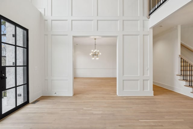 spare room featuring a high ceiling, stairway, a decorative wall, and a notable chandelier