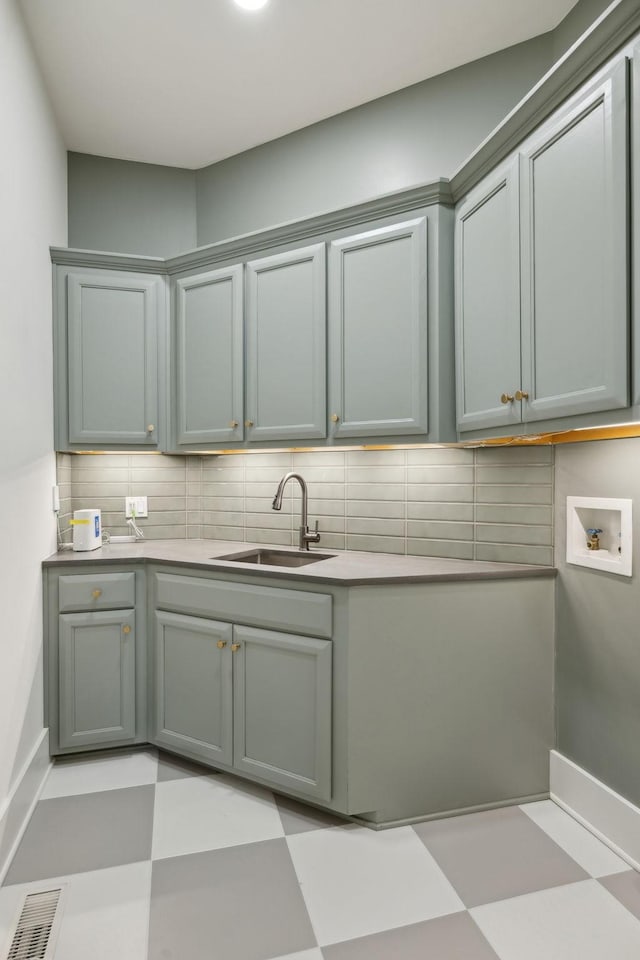 kitchen featuring light floors, backsplash, a sink, and visible vents