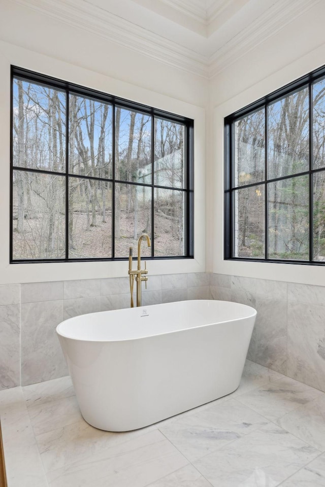 bathroom featuring marble finish floor, a freestanding tub, tile walls, and crown molding