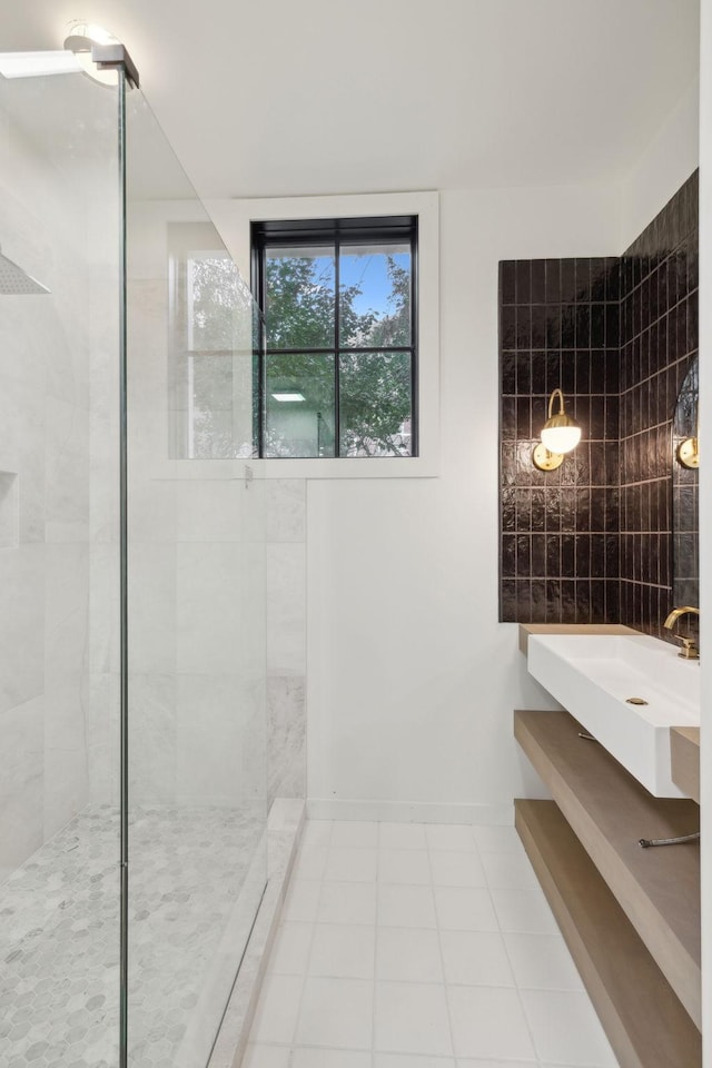 full bathroom featuring tile patterned flooring, tiled shower, a sink, and baseboards