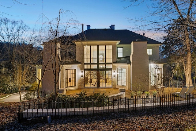 rear view of property featuring a fenced front yard and a chimney