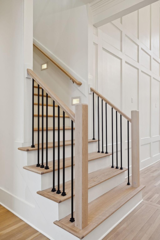 stairway featuring a decorative wall and wood finished floors