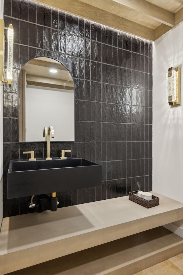 bathroom featuring beamed ceiling and backsplash