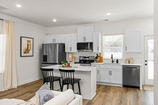 kitchen with visible vents, stainless steel appliances, a sink, and a center island