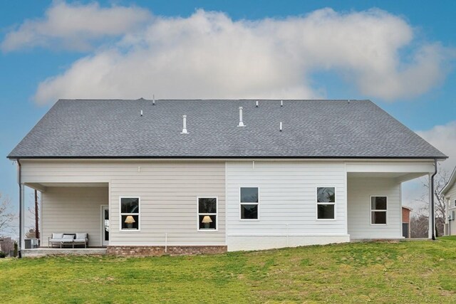 back of house with a patio, a lawn, and roof with shingles