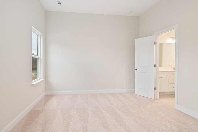 spare room with a sink, baseboards, and light colored carpet