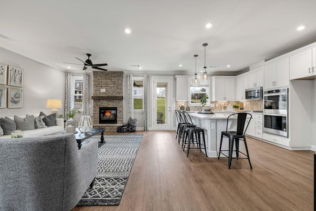 kitchen featuring open floor plan, appliances with stainless steel finishes, white cabinets, and a kitchen breakfast bar