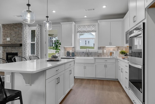 kitchen with a stone fireplace, a breakfast bar area, a sink, and backsplash